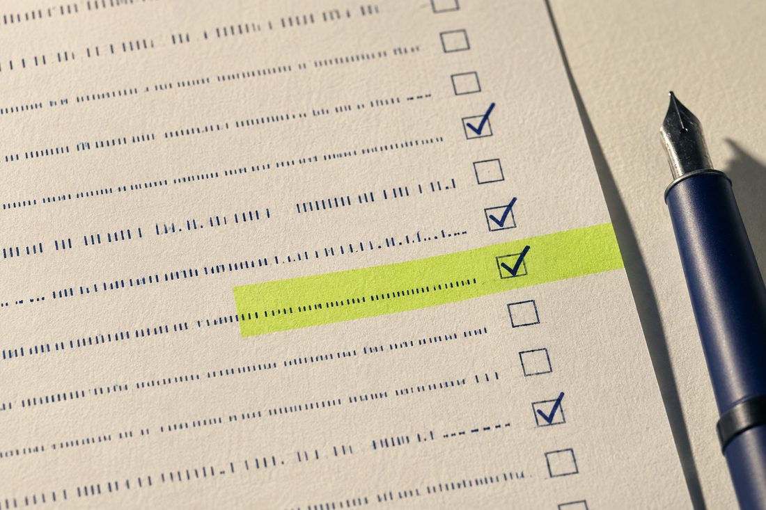 Ficha de anamnese impressa em papel creme, quatro caixas assinaladas em tinta navy e uma fita fluorescente marcando uma linha